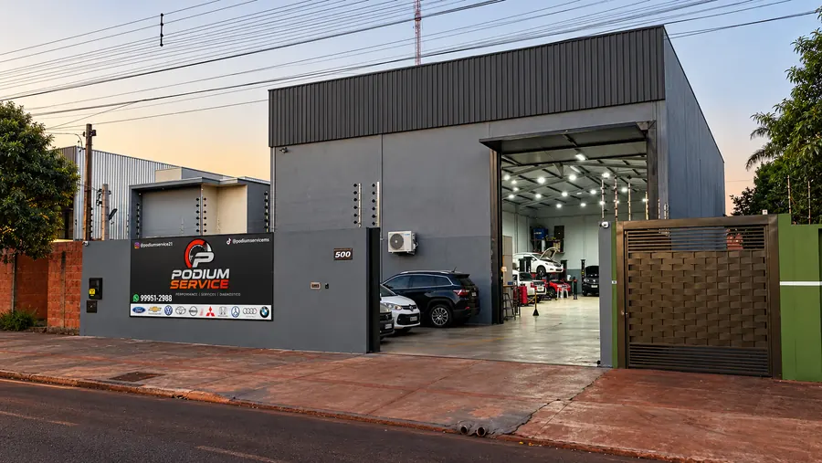 Fachada da Pódium Service em Dourados, com o galpão aberto e carros nos elevadores